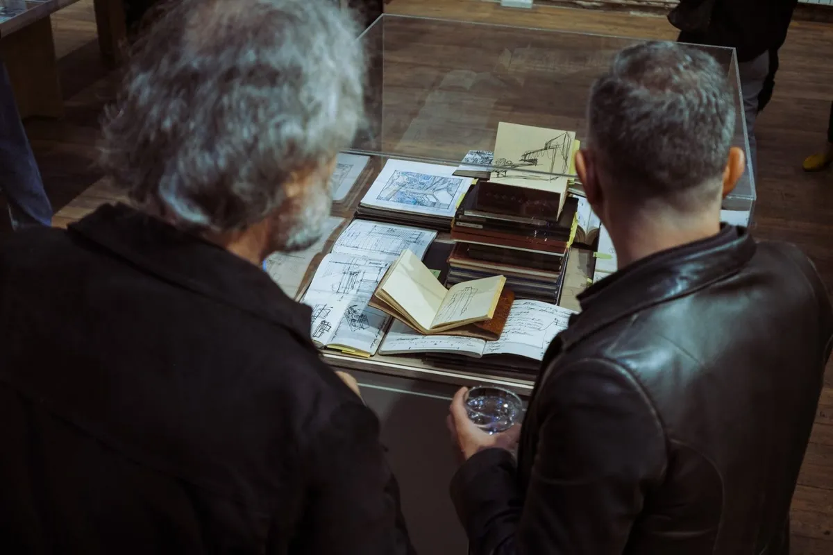 Masa Sergileri: masadaki kitap ve çizimlere bakan ziyaretçiler